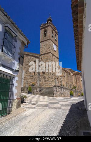 Wunderschöne Straße mit ihren typischen weißen Fassaden und die Kirche San Martin im Hintergrund in Almonaster La Stockfoto