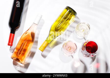 Drei Weingläser gefüllt mit Rot-, weiß- und Rosenwein, anmutig auf einem hellen, minimalistischen Hintergrund. Eine lebendige Darstellung der Vielfalt der Weine Stockfoto