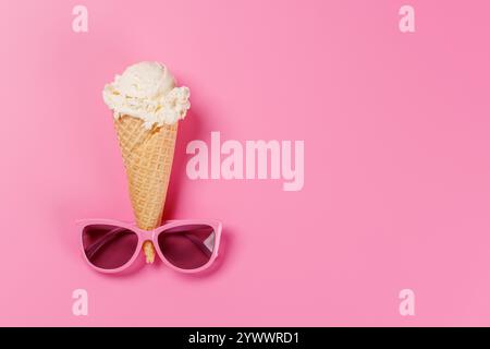 Ein verspielter Eisbecher mit stylischer Sonnenbrille vor einem leuchtend rosa Hintergrund, der Sommeratmosphäre und Spaß verströmt Stockfoto