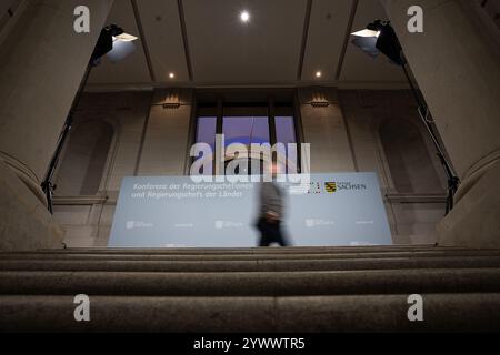 Berlin, Deutschland. Dezember 2024. Während der Ministerkonferenz (MPK) in Berlin läuft ein Mann vor einer Pressewand im Bundesrat. Quelle: Hannes P. Albert/dpa/Alamy Live News Stockfoto