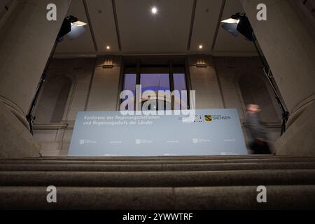 Berlin, Deutschland. Dezember 2024. Während der Ministerkonferenz (MPK) in Berlin läuft ein Mann vor einer Pressewand im Bundesrat. Quelle: Hannes P. Albert/dpa/Alamy Live News Stockfoto