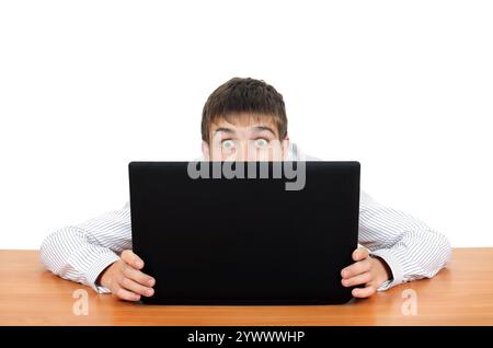 Überraschter junger Mann hinter Laptop. Isoliert auf dem weißen Hintergrund Stockfoto