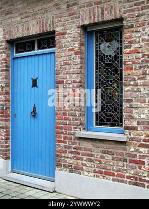 Malerisches Backsteinhaus mit blauer Tür in der Straße oder Straße, Brügge, Belgien Stockfoto