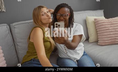 Freunde machen gemeinsam ein Selfie auf einem gemütlichen Sofa in einem hellen Wohnzimmer, um einen fröhlichen Moment zu Hause festzuhalten Stockfoto