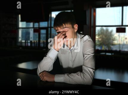 Trauriges und einsames junger Mann Porträt im dunklen Raum Stockfoto