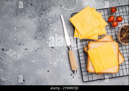 Quadratische Scheiben von verarbeitetem Cheddar-Käse in Einzelverpackung aus Kunststoff. Grauer Hintergrund. Draufsicht. Stockfoto