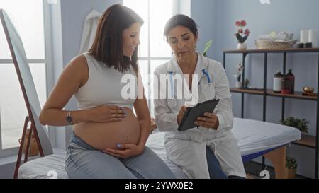 Schwangere Frau mit ärztlicher Beratung mit Tablette in einem medizinischen Klinikzimmer. Stockfoto