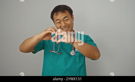 Ein junger asiatischer Arzt aus china macht eine Herzgeste mit den Händen auf weißem Hintergrund und zeigt seine fürsorgliche und mitfühlende Natur. Stockfoto