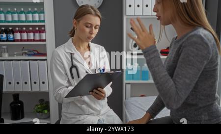 Arzt macht Notizen, während er mit dem Patienten in einer klinischen Umgebung konsultiert, mit zwei blonden Frauen, die in einem medizinischen Gespräch drinnen in einem Krankenhaus beschäftigt sind Stockfoto