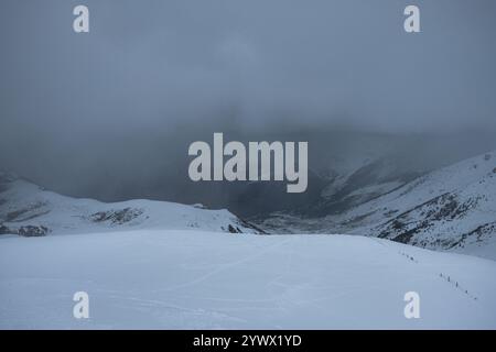 Ein Winterwunderland fängt das Vall de Boí in den Pyrenäen ein, wo Schnee den Boden bedeckt und dichter Nebel die fernen Berge bedeckt. Das ruhige A Stockfoto