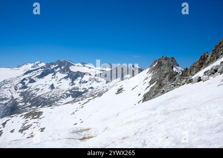 Die atemberaubende Berglandschaft zeigt schneebedeckte Gipfel und felsige Grate unter einem leuchtend blauen Himmel. Diese atemberaubende Aussicht von Vermiglio aus Stockfoto