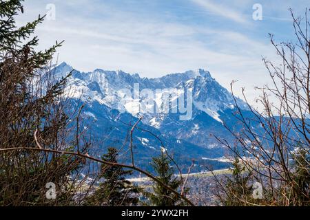 Majestätische schneebedeckte Berggipfel erheben sich im Winter in Garmisch-Partenkirchen, Bayern, die die Schönheit der Natur zeigen. Umliegende Bäume Rahmen t Stockfoto