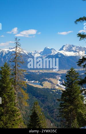 Ein atemberaubender Blick aus der Höhe zeigt die winterliche Schönheit von Garmisch-Partenkirchen. Schneebedeckte Gipfel dominieren den Horizont, umgeben von Evergre Stockfoto