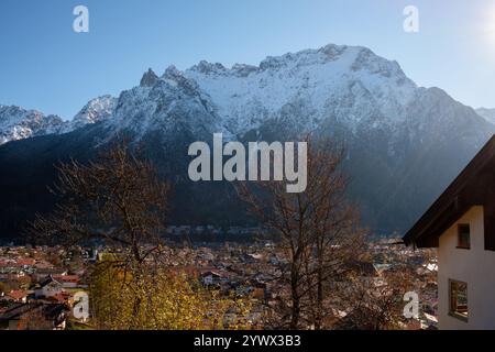 Majestätische schneebedeckte Gipfel ragen im Winter dramatisch über die gemütliche Stadt Mittenwald in Bayern. Der klare blaue Himmel zeigt ein heiteres Alpenpanorama Stockfoto