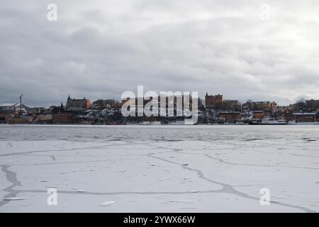 Der Winter in Stockholm bietet einen ruhigen Blick auf das gefrorene Wasser mit historischen Gebäuden auf einem Hügel mit Blick auf die eisige Weite. Stockfoto