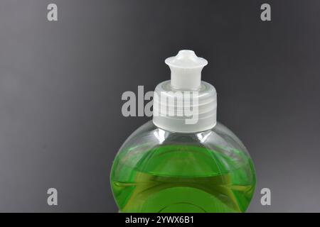 Klare, weiße, matte Flasche mit Spender, Geschirrreiniger. Eine mit einer hellgrünen, grünen Flüssigkeit gefüllte Kunststoffflasche befindet sich auf einem schwarzen Kunststoff. Stockfoto