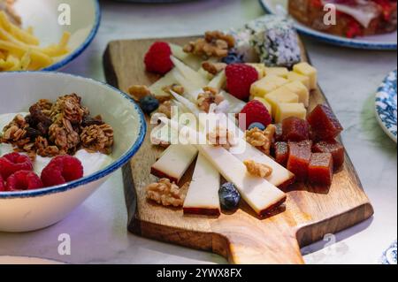 Ein wunderschönes Bild von einer Holzkäseplatte mit einer Auswahl an Käsesorten, Stockfoto