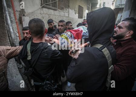 Nablus, Palästina. Dezember 2024. Bewaffnete Männer und palästinensische Menschenmengen verabschieden sich von der Leiche des jungen palästinensischen Jihad Abu Salim (27 Jahre alt). Der palästinensische Jihad Abu Salima, Mitglied der Al-Aqsa Märtyrer Brigaden, dem militärischen Flügel der Fatah-Bewegung, wurde während eines Feuerwechsels zwischen den israelischen Besatzungskräften während des Sturms auf das Lager Balata zum Märtyrer erklärt. Zwei Palästinenser wurden bei den Zusammenstößen während der Militäroperation ebenfalls verletzt. Quelle: SOPA Images Limited/Alamy Live News Stockfoto