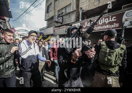 Nablus, Palästina. Dezember 2024. Bewaffnete Männer und palästinensische Menschenmengen verabschieden sich von der Leiche des jungen palästinensischen Jihad Abu Salim (27 Jahre alt). Der palästinensische Jihad Abu Salima, Mitglied der Al-Aqsa Märtyrer Brigaden, dem militärischen Flügel der Fatah-Bewegung, wurde während eines Feuerwechsels zwischen den israelischen Besatzungskräften während des Sturms auf das Lager Balata zum Märtyrer erklärt. Zwei Palästinenser wurden bei den Zusammenstößen während der Militäroperation ebenfalls verletzt. Quelle: SOPA Images Limited/Alamy Live News Stockfoto