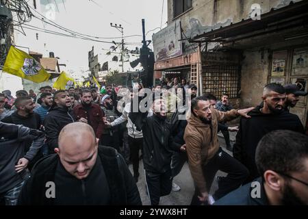 Nablus, Palästina. Dezember 2024. Bewaffnete Männer und palästinensische Menschenmengen verabschieden sich von der Leiche des jungen palästinensischen Jihad Abu Salim (27 Jahre alt). Der palästinensische Jihad Abu Salima, Mitglied der Al-Aqsa Märtyrer Brigaden, dem militärischen Flügel der Fatah-Bewegung, wurde während eines Feuerwechsels zwischen den israelischen Besatzungskräften während des Sturms auf das Lager Balata zum Märtyrer erklärt. Zwei Palästinenser wurden bei den Zusammenstößen während der Militäroperation ebenfalls verletzt. Quelle: SOPA Images Limited/Alamy Live News Stockfoto