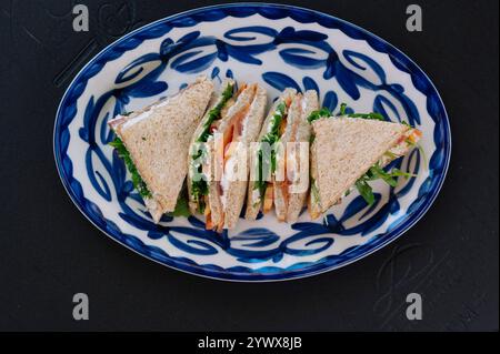 Drei köstliche geräucherte Lachs-Sandwiches sind kunstvoll auf einem Teller angeordnet. Stockfoto