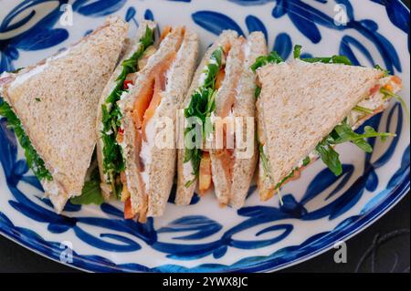 Drei köstliche geräucherte Lachs-Sandwiches sind kunstvoll auf einem Teller angeordnet. Stockfoto