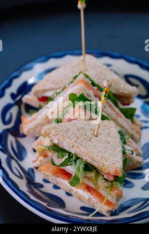 Drei köstliche geräucherte Lachs-Sandwiches sind kunstvoll auf einem Teller angeordnet. Stockfoto