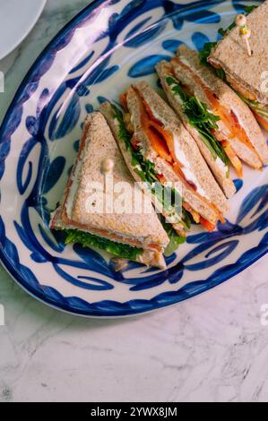 Drei köstliche geräucherte Lachs-Sandwiches sind kunstvoll auf einem Teller angeordnet. Stockfoto