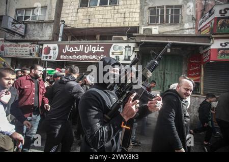 Nablus, Palästina. Dezember 2024. Bewaffnete Männer und palästinensische Menschenmengen verabschieden sich von der Leiche des jungen palästinensischen Jihad Abu Salim (27 Jahre alt). Der palästinensische Jihad Abu Salima, Mitglied der Al-Aqsa Märtyrer Brigaden, dem militärischen Flügel der Fatah-Bewegung, wurde während eines Feuerwechsels zwischen den israelischen Besatzungskräften während des Sturms auf das Lager Balata zum Märtyrer erklärt. Zwei Palästinenser wurden bei den Zusammenstößen während der Militäroperation ebenfalls verletzt. (Foto: Nasser Ishtayeh/SOPA Images/SIPA USA) Credit: SIPA USA/Alamy Live News Stockfoto