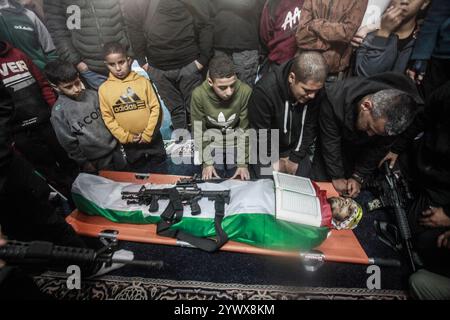 Nablus, Palästina. Dezember 2024. ANMERKUNG DES HERAUSGEBERS : Bild zeigt den Tod Verwandte und Freunde des Märtyrers legen den Heiligen Koran und sein Gewehr auf den Körper des jungen palästinensischen Jihad Abu Salim (27 Jahre alt). Der palästinensische Jihad Abu Salima, Mitglied der Al-Aqsa Märtyrer Brigaden, dem militärischen Flügel der Fatah-Bewegung, wurde während eines Feuerwechsels zwischen den israelischen Besatzungskräften während des Sturms auf das Lager Balata zum Märtyrer erklärt. Zwei Palästinenser wurden bei den Zusammenstößen während der Militäroperation ebenfalls verletzt. Quelle: SOPA Images Limited/Alamy Live News Stockfoto