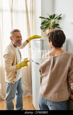 Ein fröhliches Paar teilt einen wunderbaren Moment, während sie ihre Küche harmonisch reinigen. Stockfoto