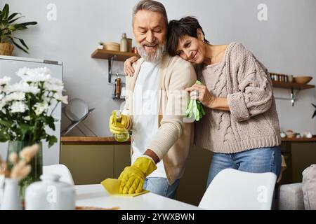 Ein glückliches, reifes Paar sorgt für eine einladende Küche und teilt warme Momente und lacht. Stockfoto