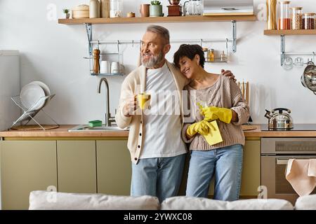 Ein liebevolles Paar teilt einen zärtlichen Moment, während es ihre fröhliche Küche zusammen aufräumt Stockfoto