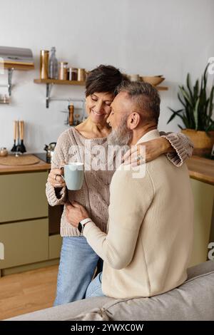 Ein liebevolles Paar umarmt sich herzlich und genießt gemeinsam Kaffee in einer stilvollen Küche. Stockfoto