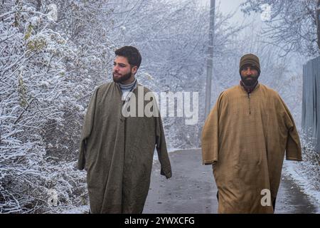 Srinagar, Indien. Dezember 2024. Die Menschen laufen am 12. Dezember 2024 unter frischem Schneefall im Charar i Shareef des Budgam-Bezirks. (Foto von Danish Showkat /SIPA USA) Credit: SIPA USA/Alamy Live News Stockfoto