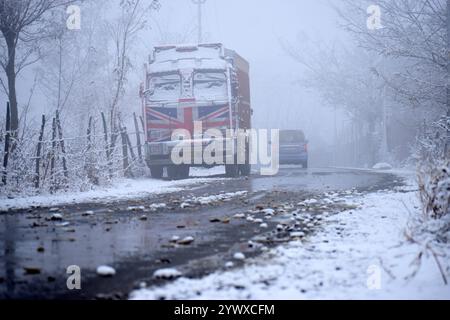 Srinagar, Indien. Dezember 2024. Vechiles bewegen sich durch die schneebedeckte Straße nach neuem Schneefall am 12. Dezember 2024 in Charar i Shareef im Budgam District. (Foto von Danish Showkat /SIPA USA) Credit: SIPA USA/Alamy Live News Stockfoto