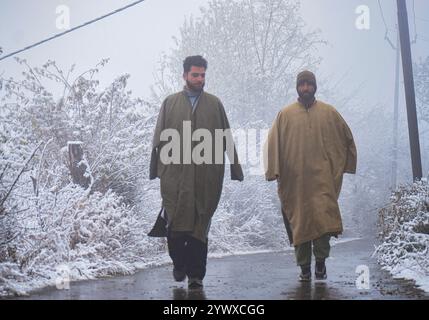 Srinagar, Indien. Dezember 2024. Die Menschen laufen am 12. Dezember 2024 unter frischem Schneefall im Charar i Shareef des Budgam-Bezirks. (Foto von Danish Showkat /SIPA USA) Credit: SIPA USA/Alamy Live News Stockfoto