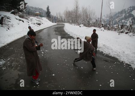 Srinagar, Indien. Dezember 2024. Frischer Schneefall in Heerpora Shopian im Süden Kaschmirs. Die Leute laufen, während die Jungen nach dem Neuschnee mit Schnee spielen. (Foto: Nisar UL Haq Allaie/Pacific Press) Credit: Pacific Press Media Production Corp./Alamy Live News Stockfoto