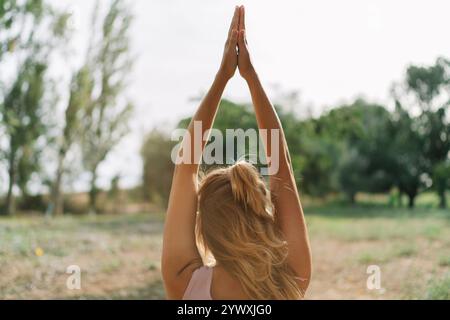 Eine Frau, die in einer ruhigen Umgebung im Freien inmitten von Grün meditiert und Entspannung und natürliche Harmonie bietet. Stockfoto