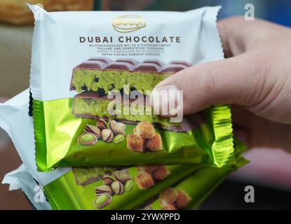 Hamburg, Deutschland. Dezember 2024. Ein Mitarbeiter in einem Kiosk hält mehrere Tische Dubai-Schokolade in der Hand. Quelle: Marcus Brandt/dpa/Alamy Live News Stockfoto