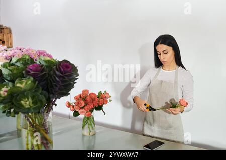 Eine hingebungsvolle Floristin arrangiert frische Blumen in ihrem lebhaften Geschäft, um ihr kleines Geschäft zu pflegen. Stockfoto