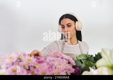 Eine engagierte Floristin arrangiert sorgfältig bunte Blüten, während sie ihr Handwerk im Geschäft genießt. Stockfoto