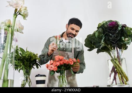 Ein talentierter Blumenhändler arrangiert in seinem Geschäft auf fachkundige Weise wunderschöne Rosen mit einem fröhlichen Lächeln. Stockfoto
