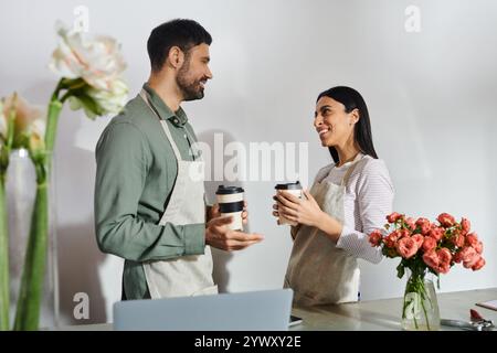 Zwei Floristen teilen sich einen Moment, während sie sich in ihrem gemütlichen Geschäft in der Nähe von Blumenarrangements unterhalten. Stockfoto