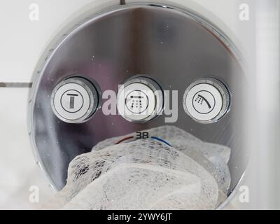 Closeup of three buttons on a modern shower control panel, to activate the water delivery and alter the spray output. Stockfoto