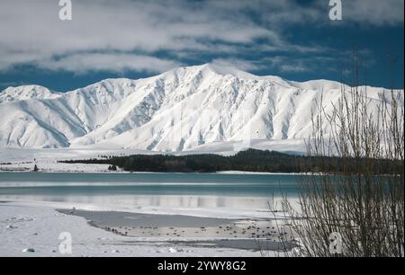 Der gefrorene See Tekapo mit schneebedeckten Gipfeln des Aoraki/Mount Cook National Park im Hintergrund - im Winter mit Schnee bedeckt Stockfoto