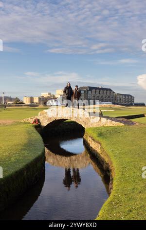 Der Alte Kurs. St. Andrews. Fife. Schottland, Großbritannien. Dezember 2024. Oliwer aus Schweden kam nach St. Andrews, um mit seinem Freund Duncan aus Edinburgh Golf auf dem Old Course zu spielen, nur um festzustellen, dass der Platz wegen Eis auf den Greens geschlossen war. Stattdessen entschied man sich, in die Fußstapfen berühmter Champions zu treten und posierte für Fotos auf der Swilken-Brücke, was wie mitten im Sommer aussah! (Foto: David Mollison/Alamy Live News Stockfoto