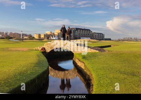 Der Alte Kurs. St. Andrews. Fife. Schottland, Großbritannien. Dezember 2024. Oliwer aus Schweden kam nach St. Andrews, um mit seinem Freund Duncan aus Edinburgh Golf auf dem Old Course zu spielen, nur um festzustellen, dass der Platz wegen Eis auf den Greens geschlossen war. Stattdessen entschied man sich, in die Fußstapfen berühmter Champions zu treten und posierte für Fotos auf der Swilken-Brücke, was wie mitten im Sommer aussah! (Foto: David Mollison/Alamy Live News Stockfoto