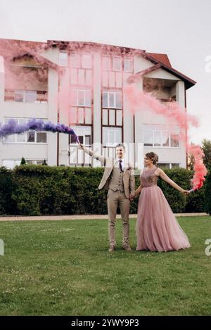 Braut in Lavendelkleid und Bräutigam auf grüner Wiese mit farbigem Rauch Stockfoto