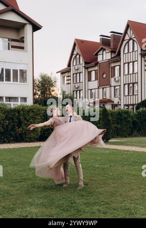 Braut in Lavendelkleid und Bräutigam auf grüner Wiese mit farbigem Rauch Stockfoto